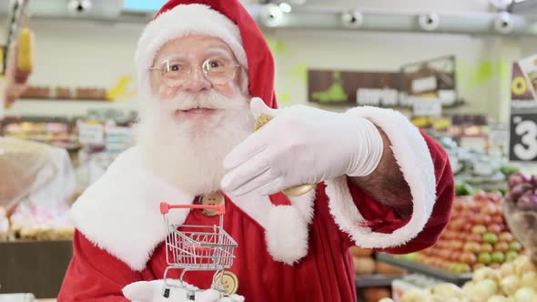 Santa Claus doing grocery shopping at the supermarket, he is showing a mini cart