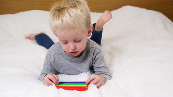 Little boy lies and plays an educational game. Colorful antistress sensory toy