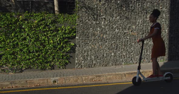 Mixed race woman riding electric scooter on street alt