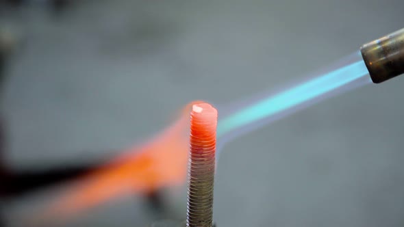 Fire of gas burner heats up red-hot the metal bolt closeup alt