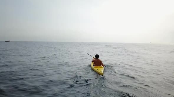 Flying above a young man kayaking on the sea