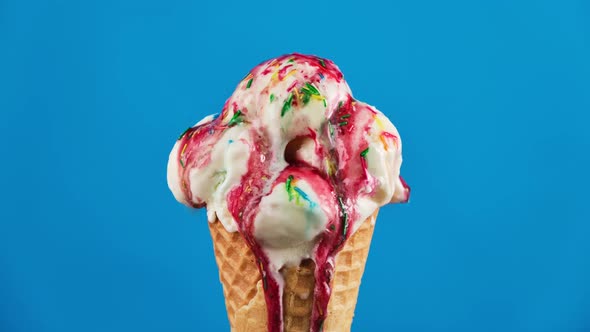 Vanilla Ice Cream with Strawberry Topping and Sprinkles in Waffle Cone Melting alt