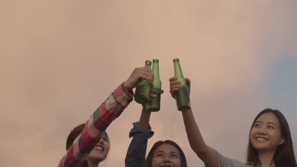 Young teen Asian woman happy friends camping in nature having fun together drinking beer.