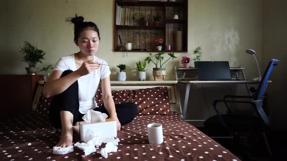 Sick Asian woman measuring temperature alt