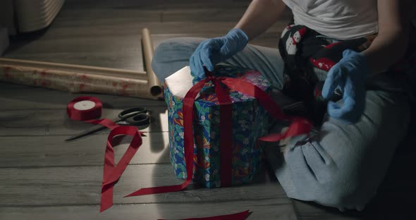 Woman Hands in Protective Gloves Packing Christmas Gift