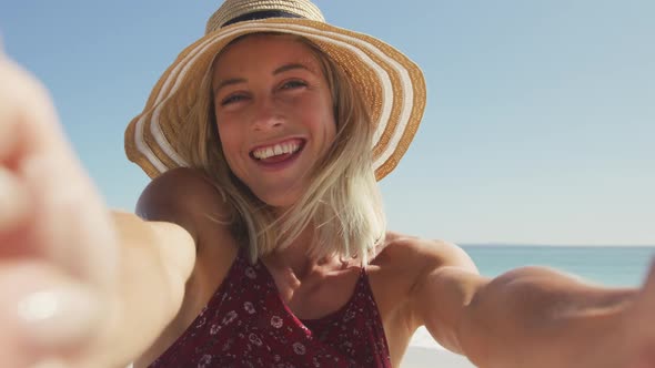 Caucasian woman sending kisses through camera at beach alt