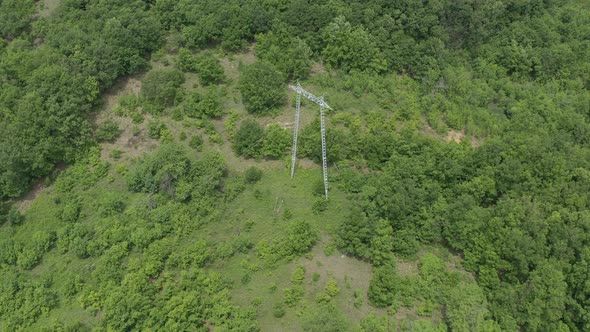 Electricity pylon and transmission cables over the forest 4K drone video alt