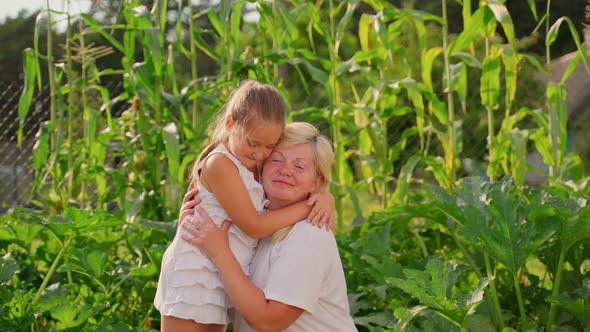 Portrait grandmother and granddaughter hugging in garden outdoors. Two females alt