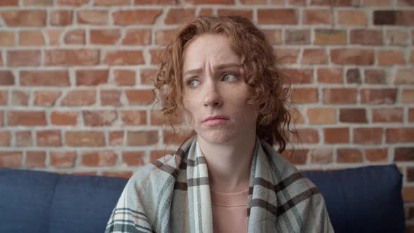 Video of caucasian young woman covered with a blanket falling down on sofa. alt