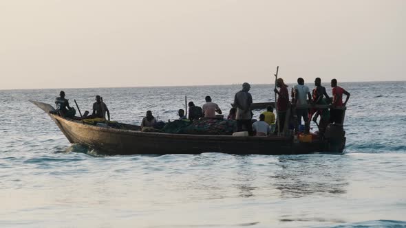 African Wooden Fishing Boat with Fishermen Sailing in Ocean Zanzibar Tanzania alt