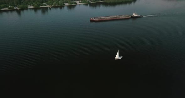 Drone Flight Over the River Overlooking the Tug Barge and Sailboat in the Evening, Sunset. Ukraine