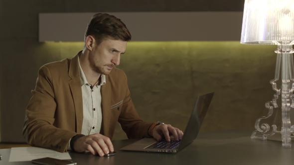 Businessman Looking With Interest At His Laptop Computer. alt