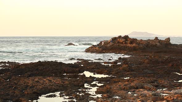 Seaside view with rocky beach and ocean waves in Fuerteventura at sunset