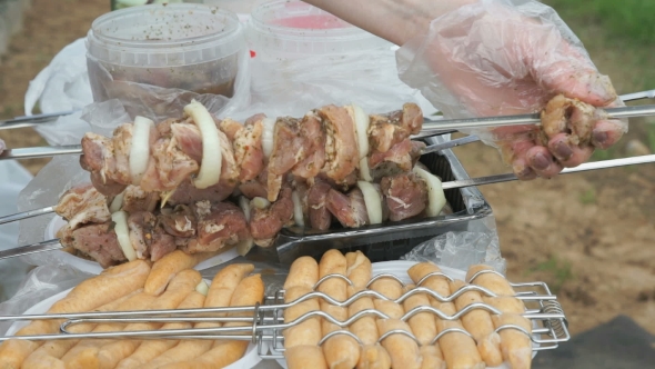 Hand Is Stringing Pieces Of Raw Meat On a Skewer alt