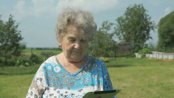 Aged Woman 80s Holding a Digital Tablet Outdoors