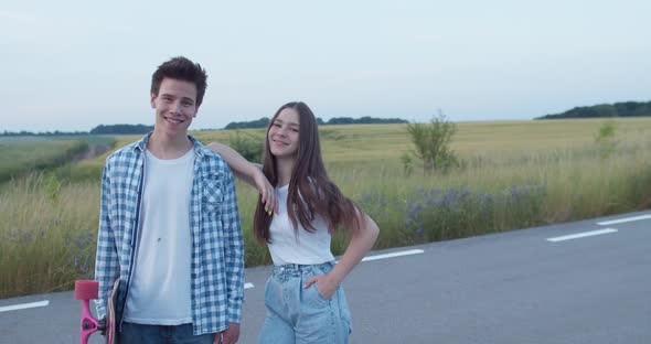 Portrait of Couple of Teenagers with Skateboard Smiling at Camera on Nature alt