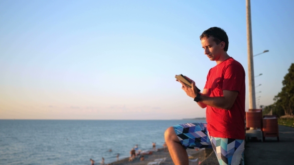 Young Handsome Man Relaxing Near The Sea Beach With Tablet Computer