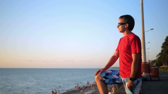 Young Handsome Man In Sunglasses Relaxing Near The Sea Beach At Sunset