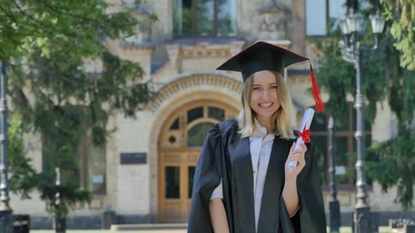 Woman in Mantle Raises Her Hands Shows Diploma alt