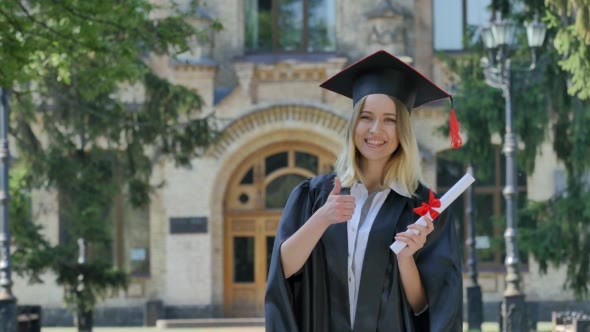 Graduand Woman in Mantle Shows Her Thumb Holding