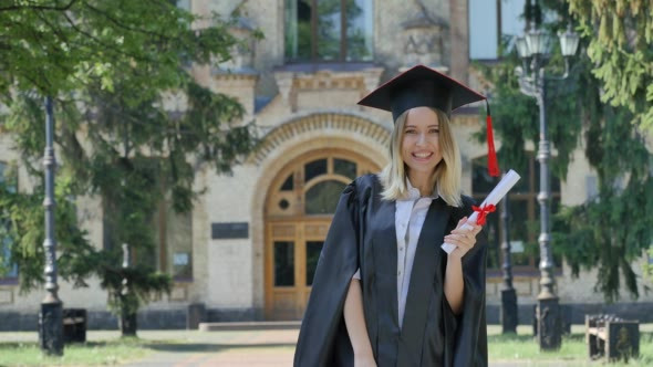 Graduand in Mantle Raises Her Fists Shows Diploma