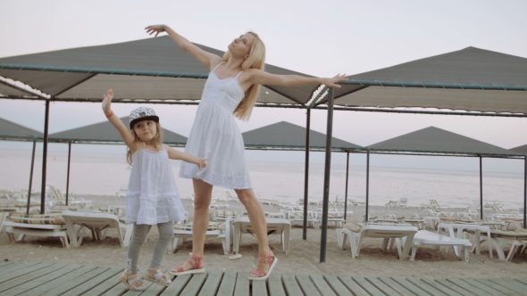 Mother Dancing With Daughter In White Dress On The Beach