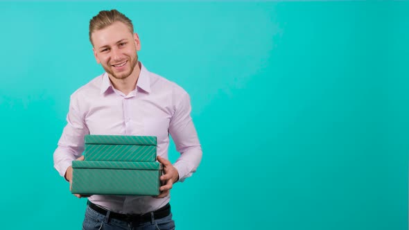 Young Handsome Man Who Gives a Gift Box From the Heart, Looking at the Camera. alt