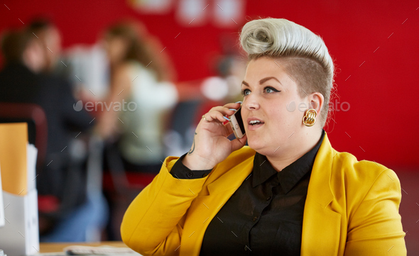 Confident female designer having a conversation on mobile phone - Stock Photo - Images