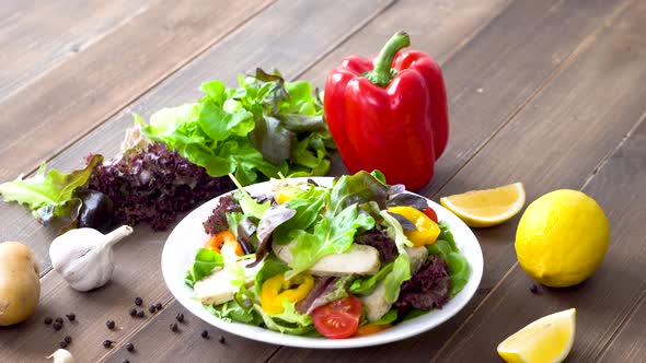 Colorful fresh homemade healthy salad with boiled chicken breast on wood table background