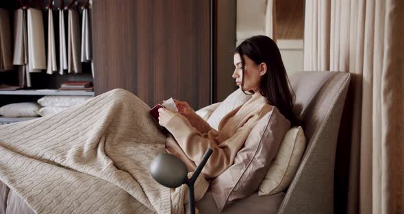 Woman Relaxing in Bed and Reading a Book in the Bedroom in the Modern House alt