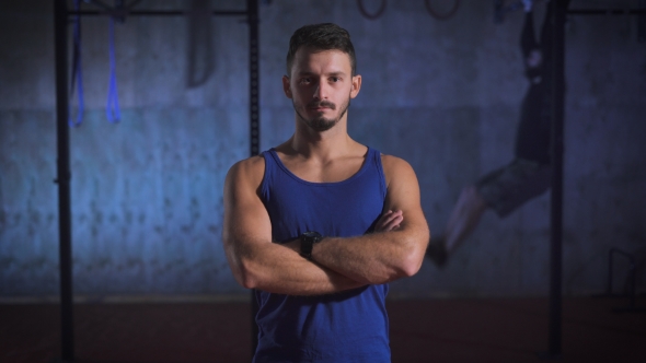 Strong Man In Blue Shirt With Arms Crossed Posing At The Gym. alt