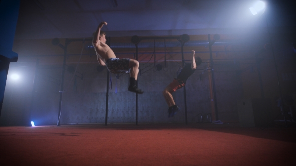 Two Athletes Doing Difficult Crossfit Exercise At The Same Time. alt