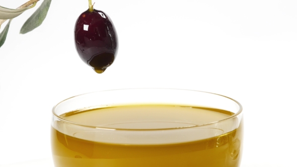 A Drop Of Olive Oil Falling From One Black Olive alt
