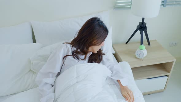 Asian attractive young woman feel shock after wake up late in bedroom in pajamas look at alarm clock alt