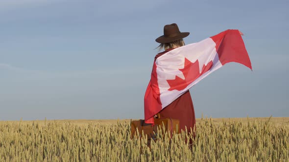 Girl with Canada flag in wheat field and blue sky on background