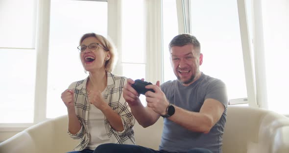 Happy Couple Sitting on the Sofa and Playing Video Games Using Controllers in Love Have Fun Playing alt
