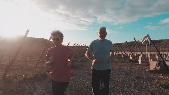 Couple of adults mature caucasian man and woman do jogging in the countryside alt