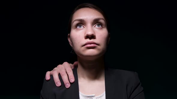 hands of unknown person from darkness touch a woman in a jacket over shoulder alt