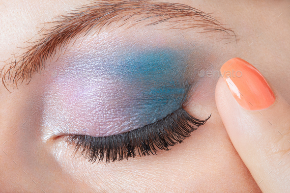 Blue eye smokey make up with finger with orange nail polish Stock Photo by andreahast