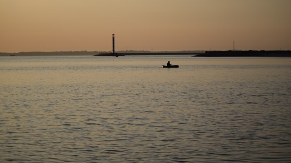 Silhouette Of Man Rows In a Boat On Water