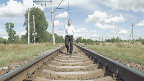 Man Walking Along Railway Tracks Toward Camera