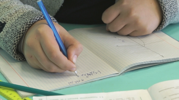 Pupil Writes Text In a Notebook Indoors