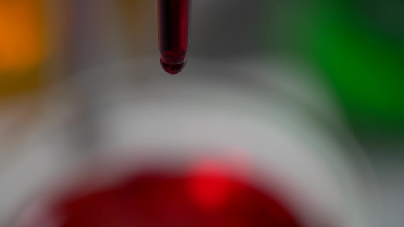 Red Liquid Dripping Into The Flask In a Laboratory alt