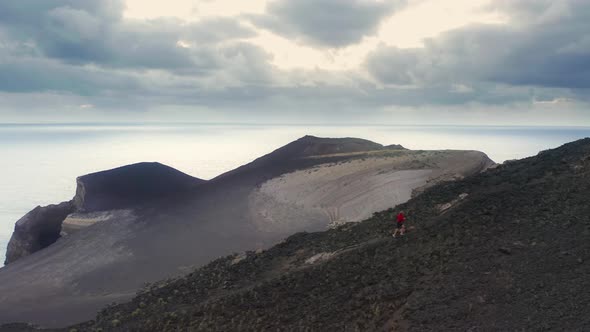 Caucasian Man Running Across a Volcanic Formation alt