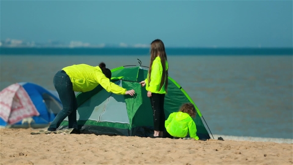 Mother With Kids Preparing a Tent On The Beach For Families.