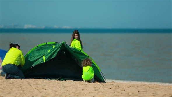 Woman With Child Establishes Tent On The Shore Of The Bay For a Family Holiday.
