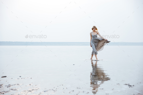 Woman in long dress walking on the beach - Stock Photo - Images