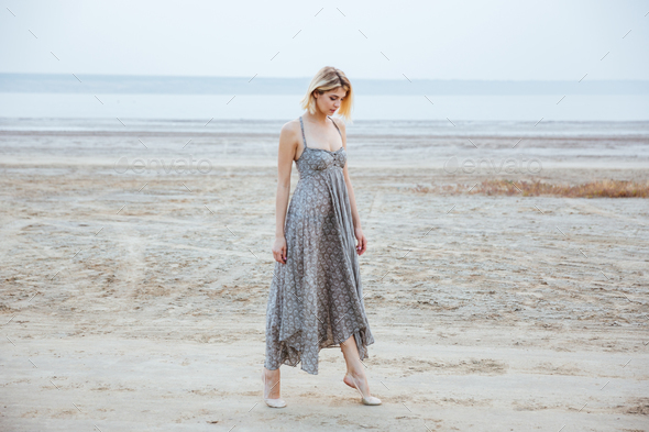 Woman in beautiful long dress walking tiptoes on the beach - Stock Photo - Images