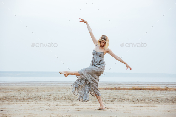 Woman dancer in long dress dancing barefoot on the beach - Stock Photo - Images