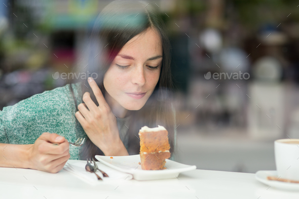young pretty woman eating a cake - Stock Photo - Images